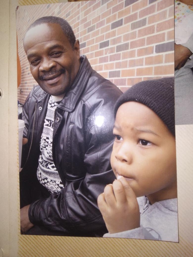 Father and son together, brick wall behind them