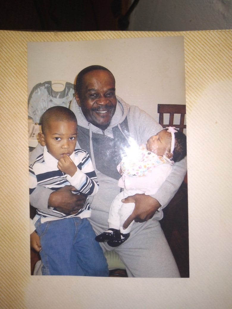 Father holding grandchildren with joy
