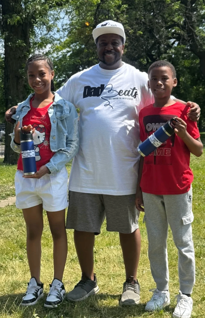 Three men in Dad-Beats shirts with arms around each other at the competition
