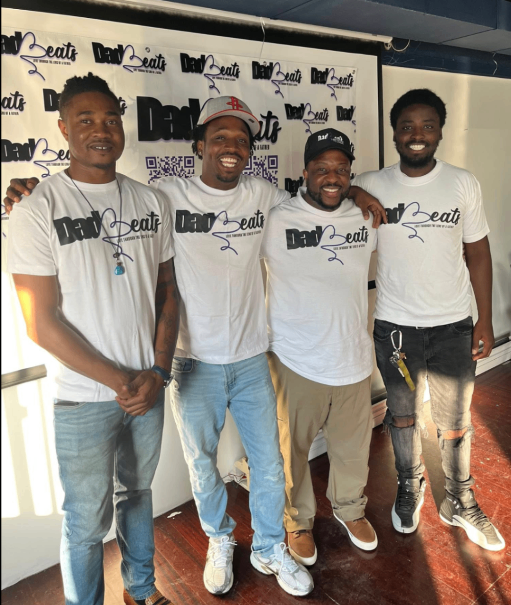 Four men in Dad-Beats shirts standing together in front of a Dad-Beats banner